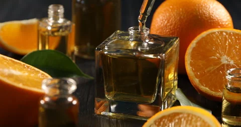 Dripping aromatic essential oil from pipette into perfume bottle among oran.. Stock-Footage 306412380
