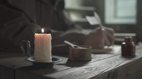 Dripping candle in a holder with a monastic scribe in the background Stock Footage 340823194