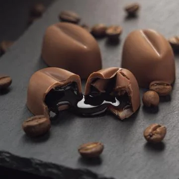 Dripping coffee syrup out of broken chocolate on black stone tray Foto stock