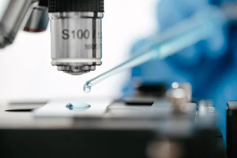 Dripping liquid onto slide under microscope to make coronavirus test in lab Stock Photos