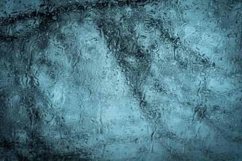 Dripping raindrops on the background of tree branches in defocus on the glass Stock Photos