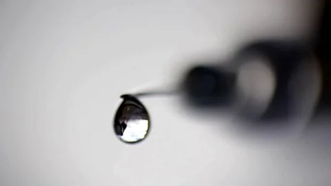 Dripping syringe against blurred gray background. Side view, macro shot Stock-Footage 336587328
