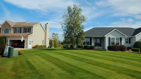 Drive along an area with typical US homes surrounded by green lawns. Stock Footage 98279213