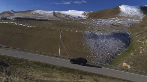 Drive a black car through the mountains. Snow caps of the mountains.  Stock Footage 292880359