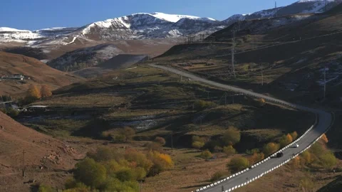Drive a black car through the mountains. Snow caps of the mountains.  Stock Footage 292880384