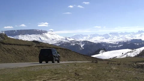 Drive a black car through the mountains. Snow caps of the mountains.  Stock Footage 292880498