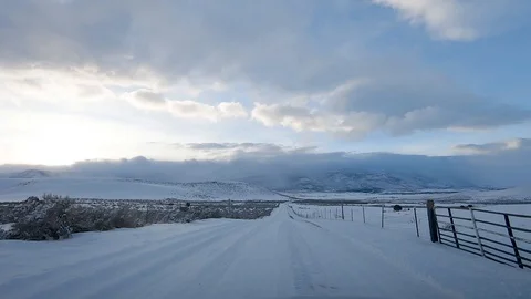 Drive Plate-POV-View forward-Snowy country road in hills-setting sun Video stock 103234801