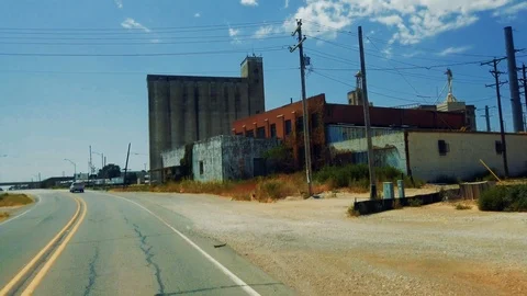 Drive straight ahead coming up to small country town grain elevator Stock Footage 114990942