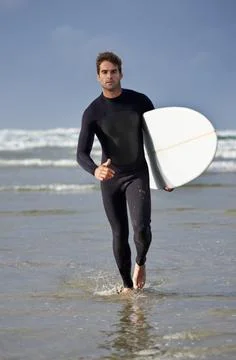 Driven to surf. Full length shot of a male surfer walking out of the water. Fotos de archivo
