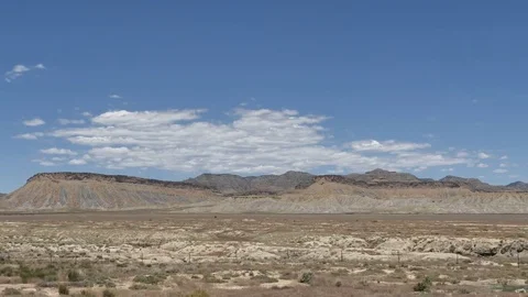 DrivePlate-SideView-Desolate Plateau Sparse Desert Vegetation Blue Sky Clouds Video stock 77153867