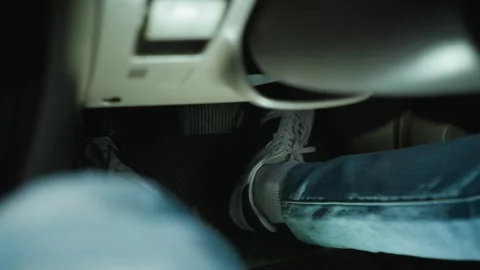 Driver actively adjusting pedals while concentrating inside urban vehicle Stock Footage 329451539