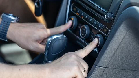 Driver Adjusting Car Climate Control on Modern Vehicle Dashboard 写真素材