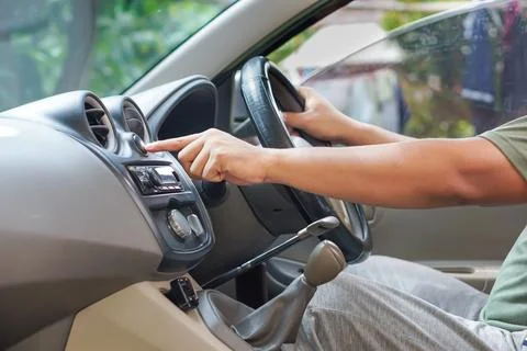 A driver adjusts the air conditioning control while seated in the driver's .. Foto stock