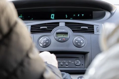 A driver adjusts the climate control settings inside a modern vehicle cabin.. Stock Photos