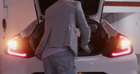 Driver adjusts gloves and opens car trunk with rubber tires Stockbeeldmateriaal 294605997