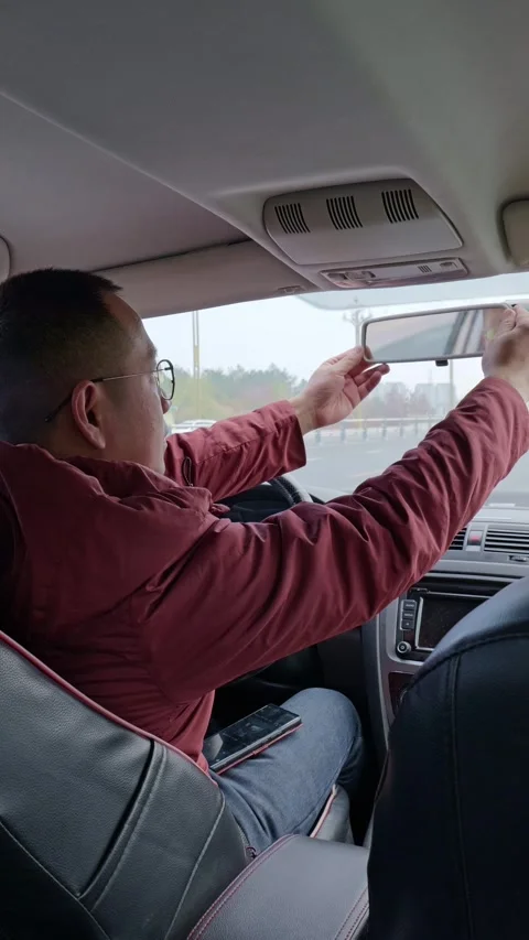 The driver adjusts the rearview mirror by hand. Stock Footage 329168158