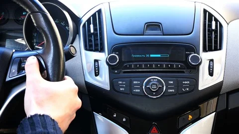 The driver adjusts the volume level of the car's acoustic system on the steering Vídeos de archivo 78040633