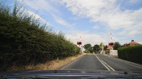 Driver approaching warning lights flashing at train level crossing uk Stock Footage 92848387