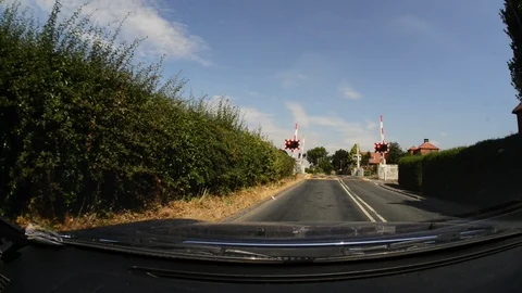 Driver approaching warning lights flashing at train level crossing uk Stock Footage 92848404