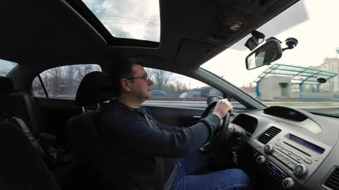 The driver behind the wheel of a car drives it along the road. He looks int.. Stock Footage 258058175
