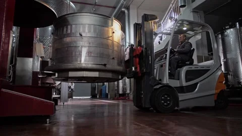 Driver behind the wheel of a forklift installs a tank with grapes into a press Stock Footage 268750515