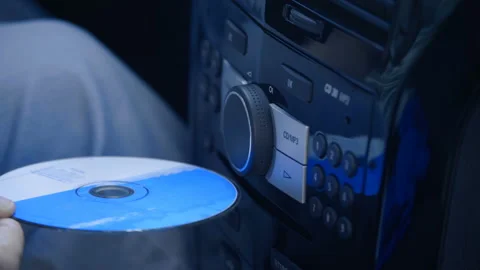 The driver in the car inserts a CD into the player and turns up the music volume Stock Footage 138279895