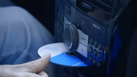 The driver in the car inserts a CD into the player and turns up the music volume Stock Footage 138279999