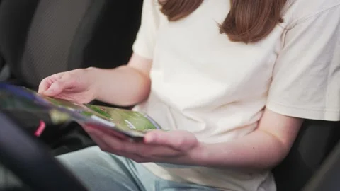 The driver in the car looks at the paper map, close-up. Holidays on a road trip Vídeo Stock 192371224