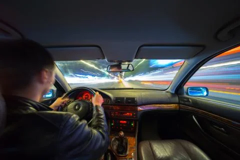 Driver in car moves at fast speed at night. Stock Photos