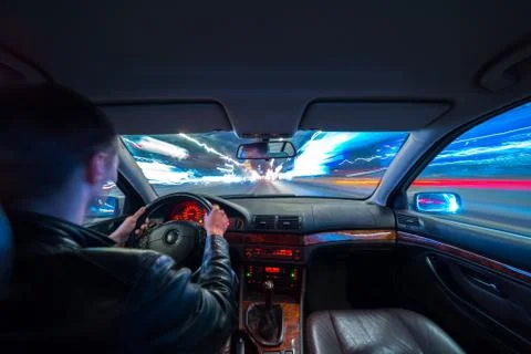 Driver in car moves at fast speed at night. Stock Photos