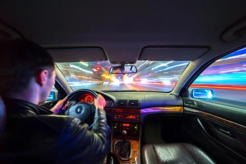 Driver in car moves at fast speed at night. Stock Photos