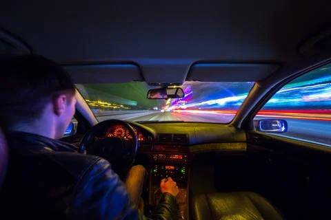 Driver in car moves at fast speed at night. Stock Photos
