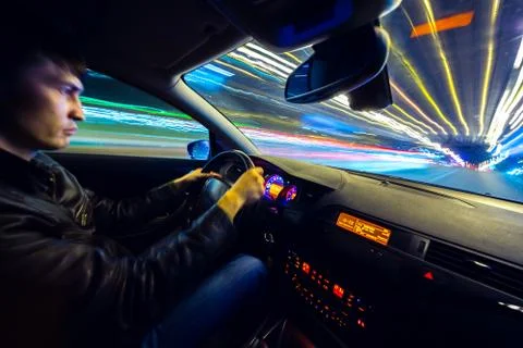 Driver in car moves at fast speed at night. Stock Photos