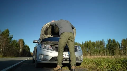 Driver of a car opened the hood on the side of a country road Stockbeeldmateriaal 254877180