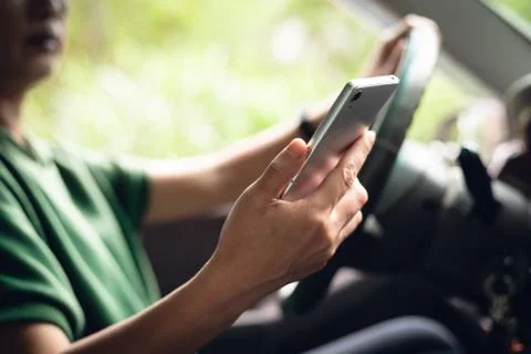 Driver with a cell phone in hand while driving Foto stock