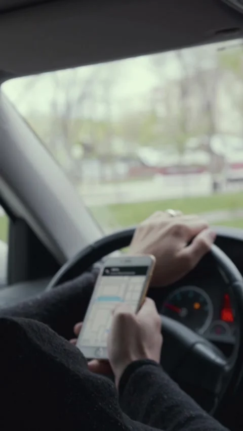 Driver checks a GPS map on a smartphone while one hand rests on the steering Video stock 346859493
