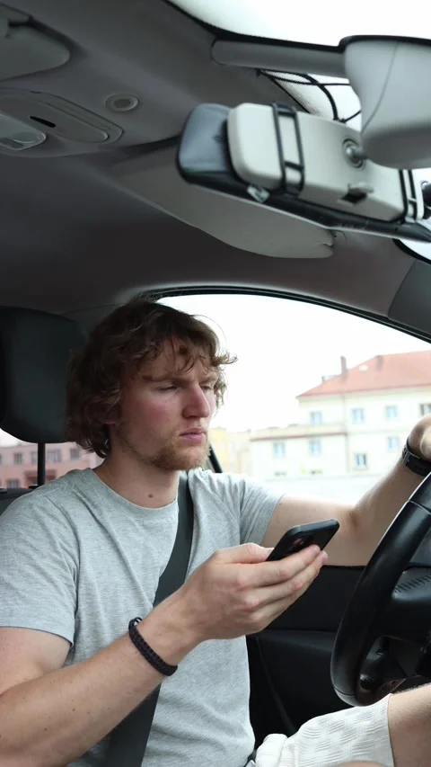 Driver checks his smartphone while steering a moving car with only one hand Stock Footage 342924094