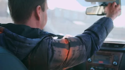 Driver checks mirror, driver inspects mirror while man observes front road Stock Footage 323797855