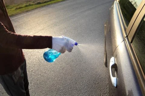 Driver cleaning car handle using sprayer Stock Photos