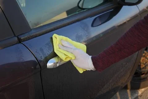 Driver cleaning car handle using antibacterial solution and cloth Stock Photos