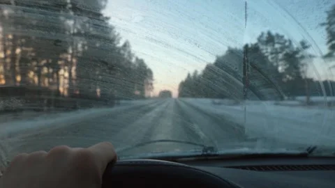 Driver cleaning frozen windshield while driving on winter road Stock Footage 302540296