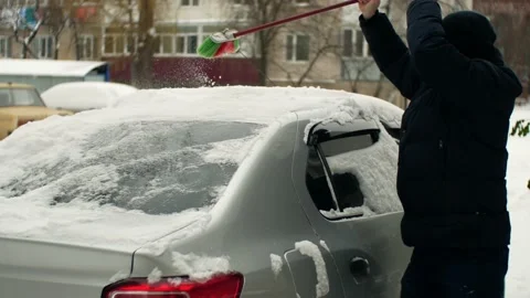 Driver cleans the car from snow after a heavy snowfall in a winter city  Stock Footage 236688435