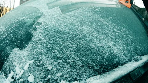 The driver cleans the car windscreen of snow and ice with a scraper,slow motion Video stock 120920874