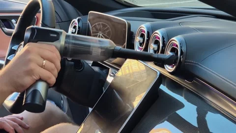 The driver cleans the car's deflectors using a cordless vacuum cleaner Stock Footage 316477196