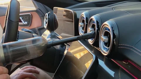 The driver cleans the car's deflectors using a cordless vacuum cleaner Stock-Footage 316477223