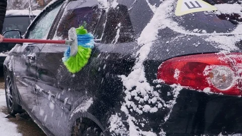 The driver clears the car from the snow closeup Stock Footage 104064411
