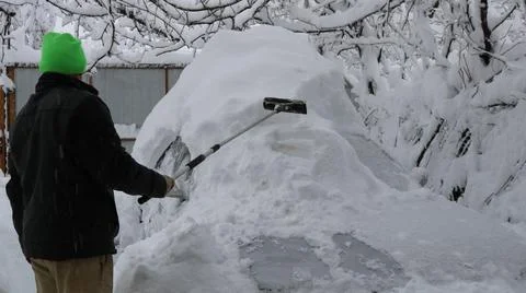 The driver clears his car of heavy snow Stock Photos