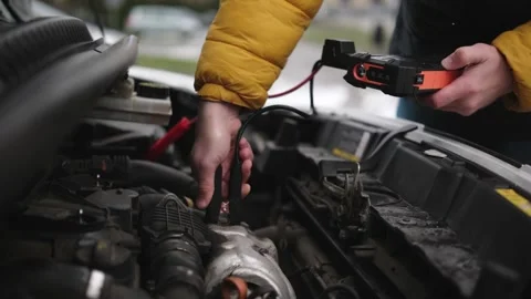 Driver Connecting A Jump Starter Battery To Car Engine Video stock 329226774
