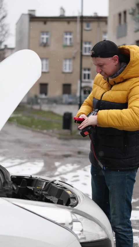 Driver Connecting Jump Starter To Car With Opened Engine Hood On Parking Video stock 329133853