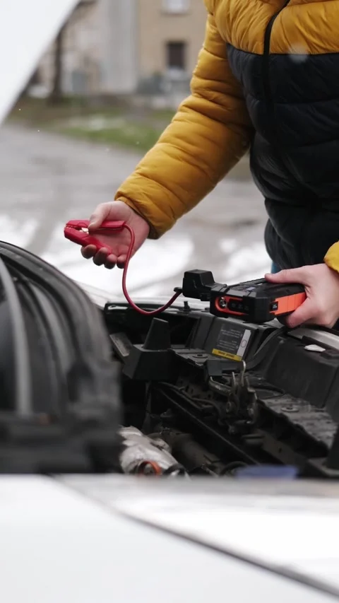 Driver Connecting Jump Starter To Car With Opened Engine Hood On Parking Stock Footage 338408031